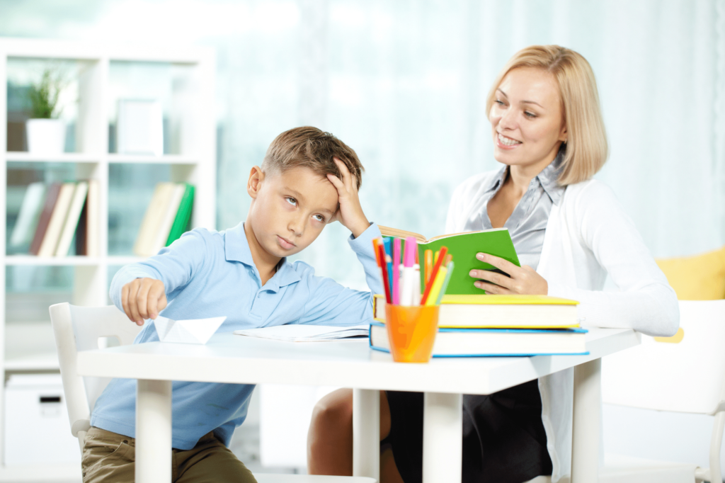 A young boy who is reluctant to write sitting at a desk bored.